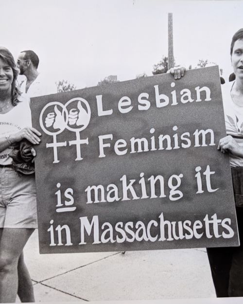 Two women holding a sign that reads Lesbian Feminism is making it in Massachusetts during the 1980 Boston Pride March