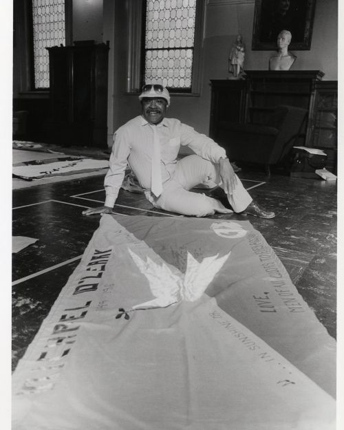 George Nolley, co-chair of Men of All Colors Together, with a panel for the Names Project AIDS quilt commemorating the life of Michael O'Leary (1949-1986), one of the group's members, signed by Men of all Colors Together Boston.