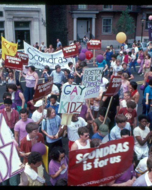 Marchers during the Gay Pride Parade carrying signs saying "Scondras is for us" down Charles Street